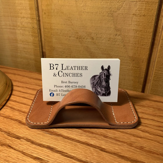 A leather business card holder on an oak table, holding a B7 Leather business card.
