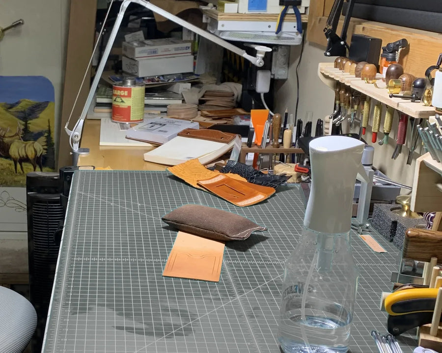 The bench in Dayton: cutting mat, cut leather, and swivel knives and stamps racked above it.