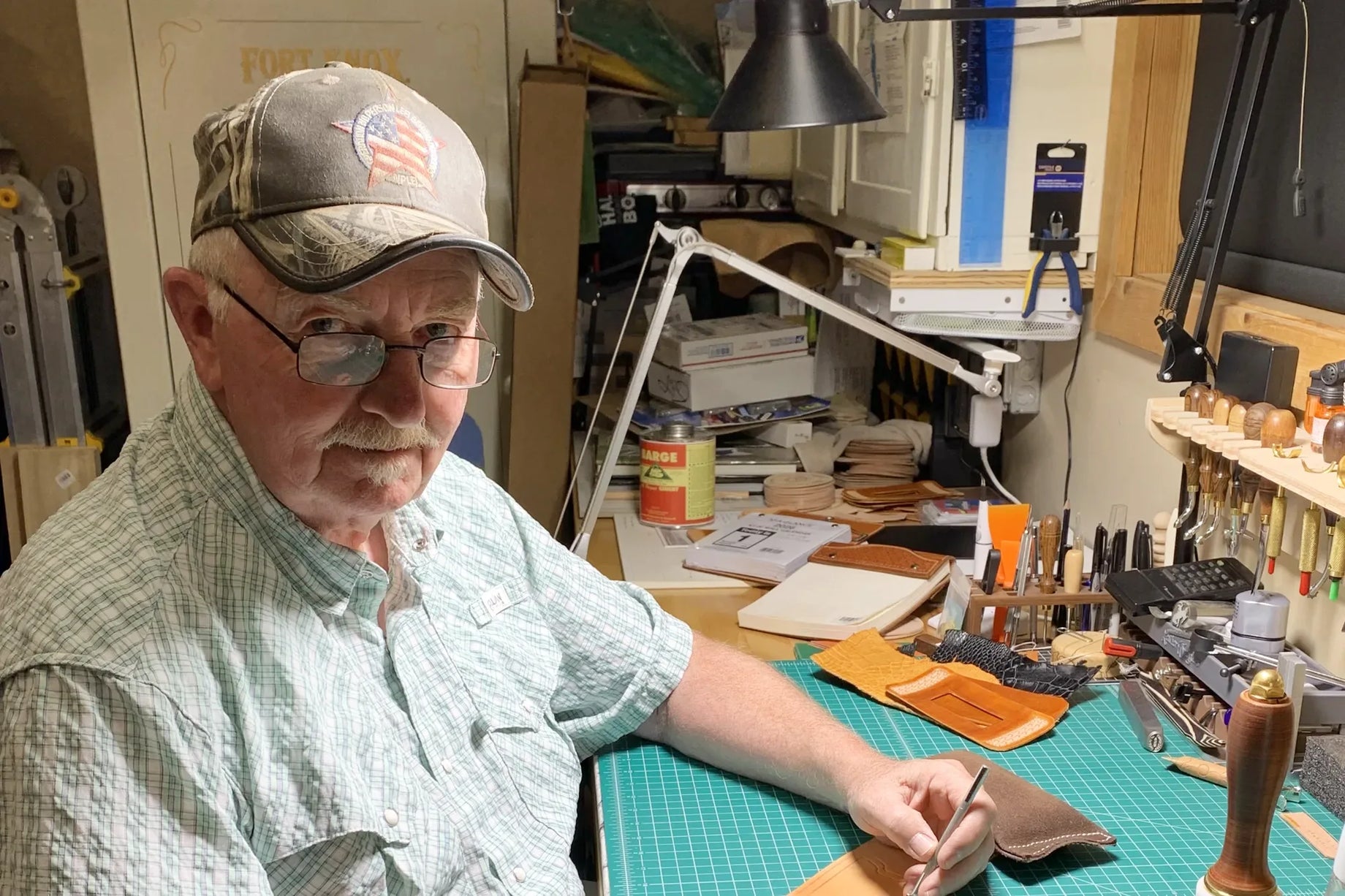 Bret Barney at his bench in Dayton, Wyoming, a piece of tooling leather under his hand.