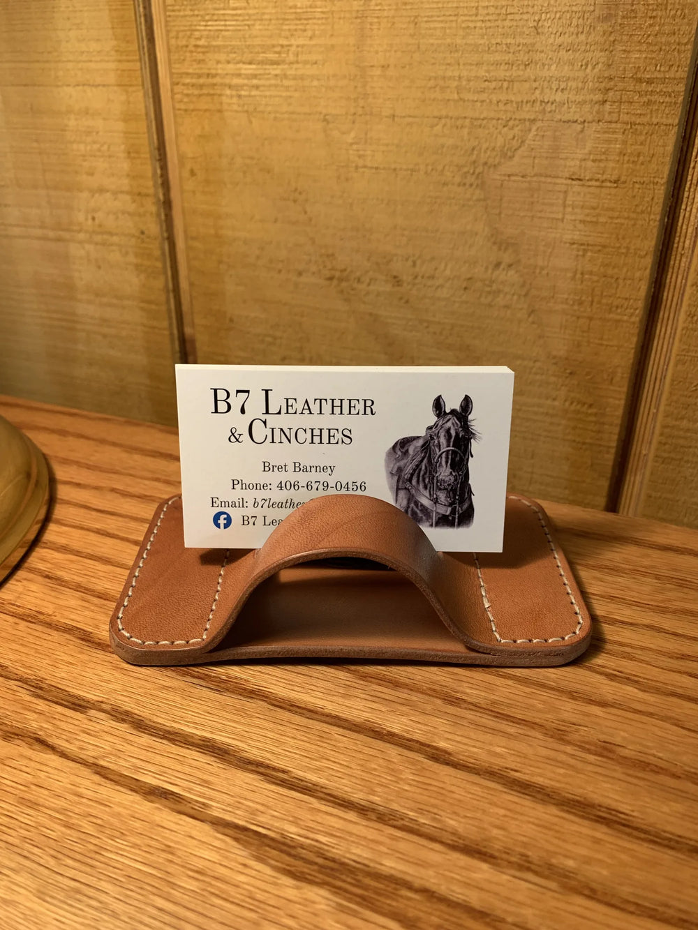 A leather business card holder on an oak table, holding a B7 Leather business card.