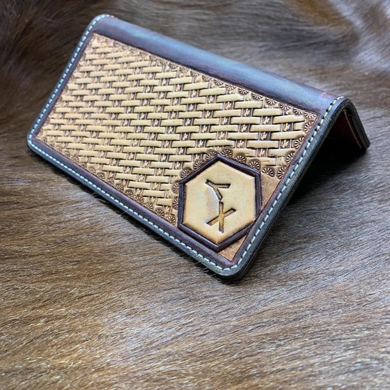 A basketweave-tooled leather checkbook cover with a ranch brand set into a hexagon panel.