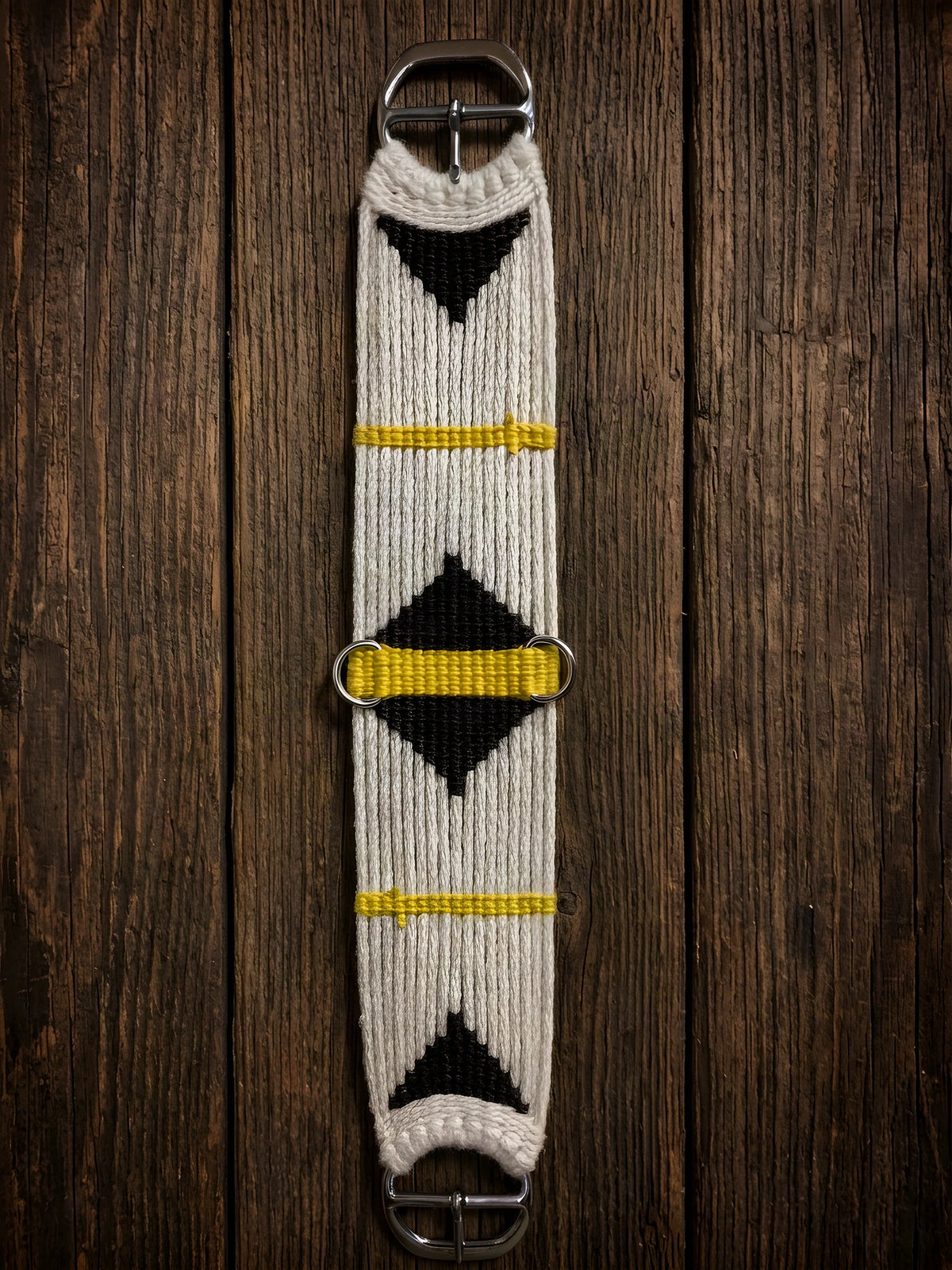 A hand-tied mohair cinch, natural body with dark diamonds and yellow bars, on barn wood