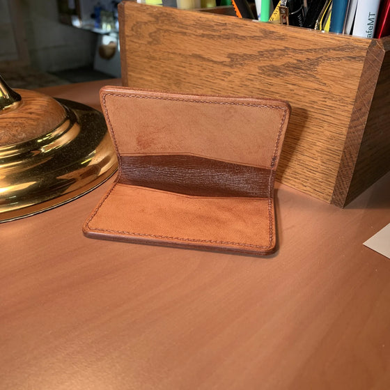 A plain leather card case, open.
