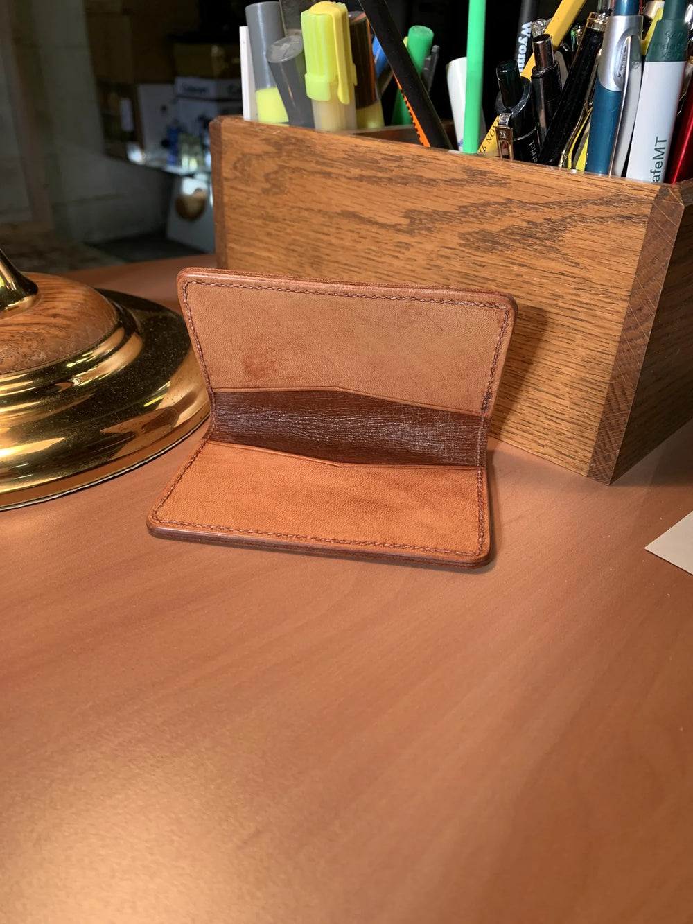 A plain leather card case, open.